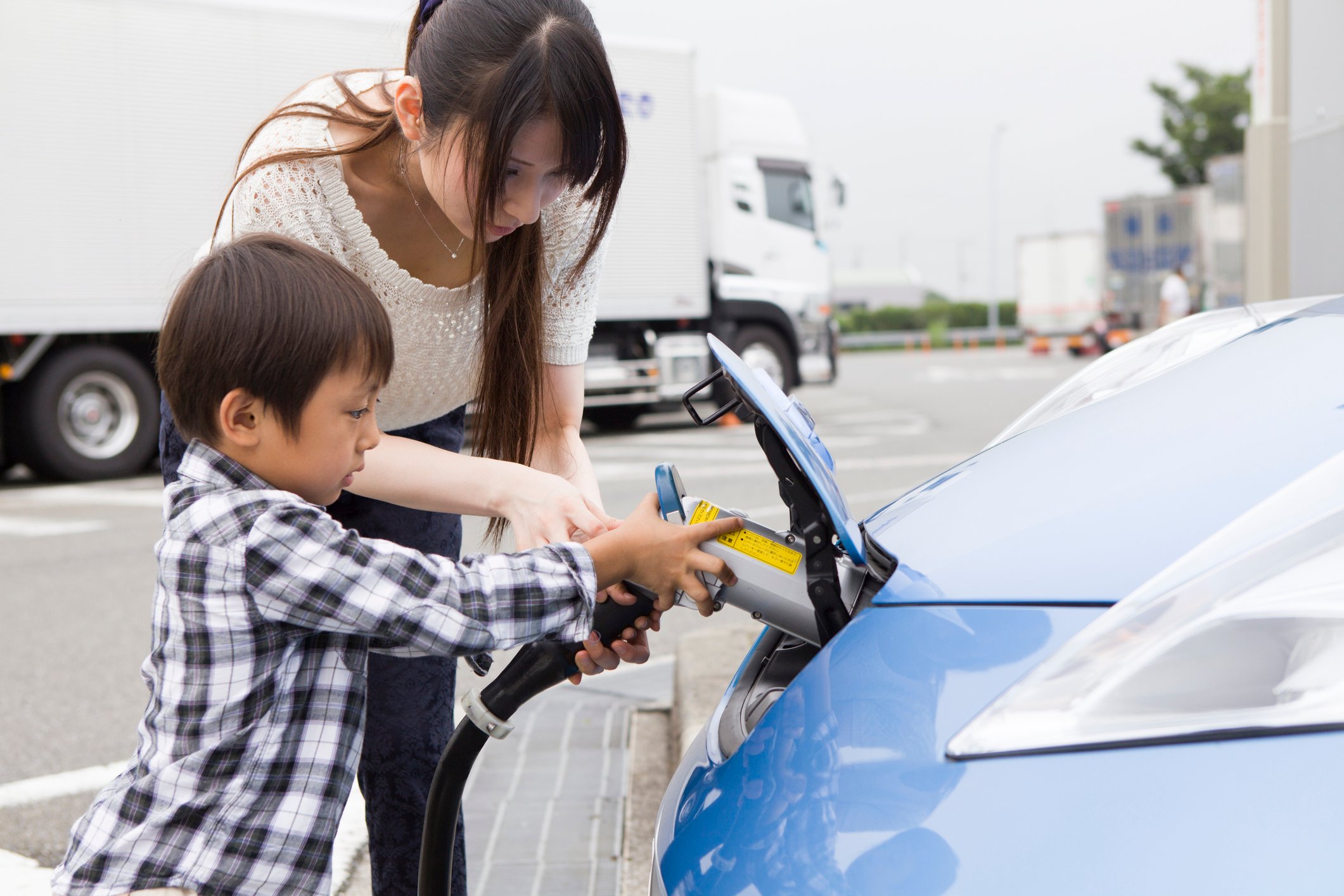 Adult and child plugging in an electric vehicle.