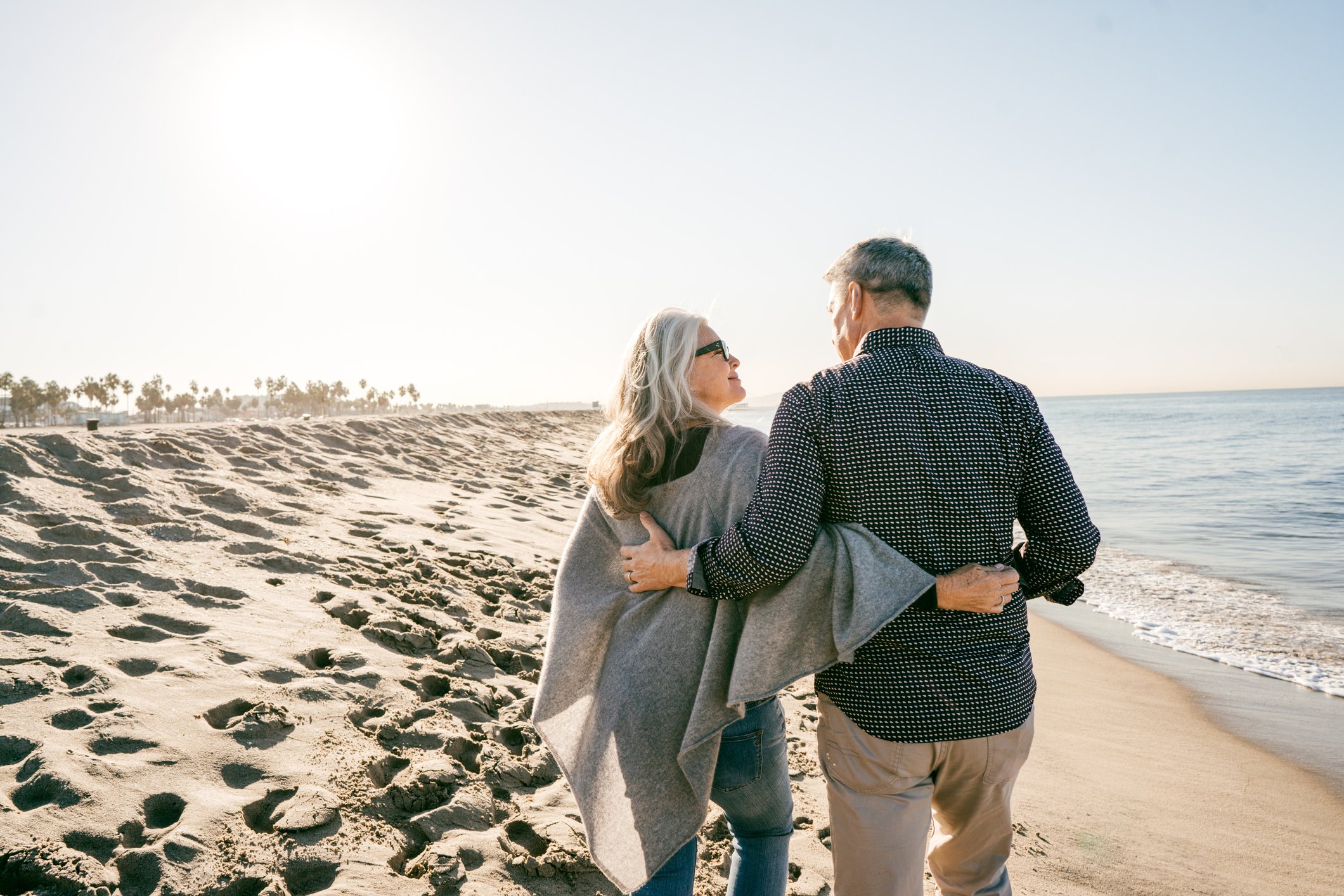 Older couple walking on a sunny beach.