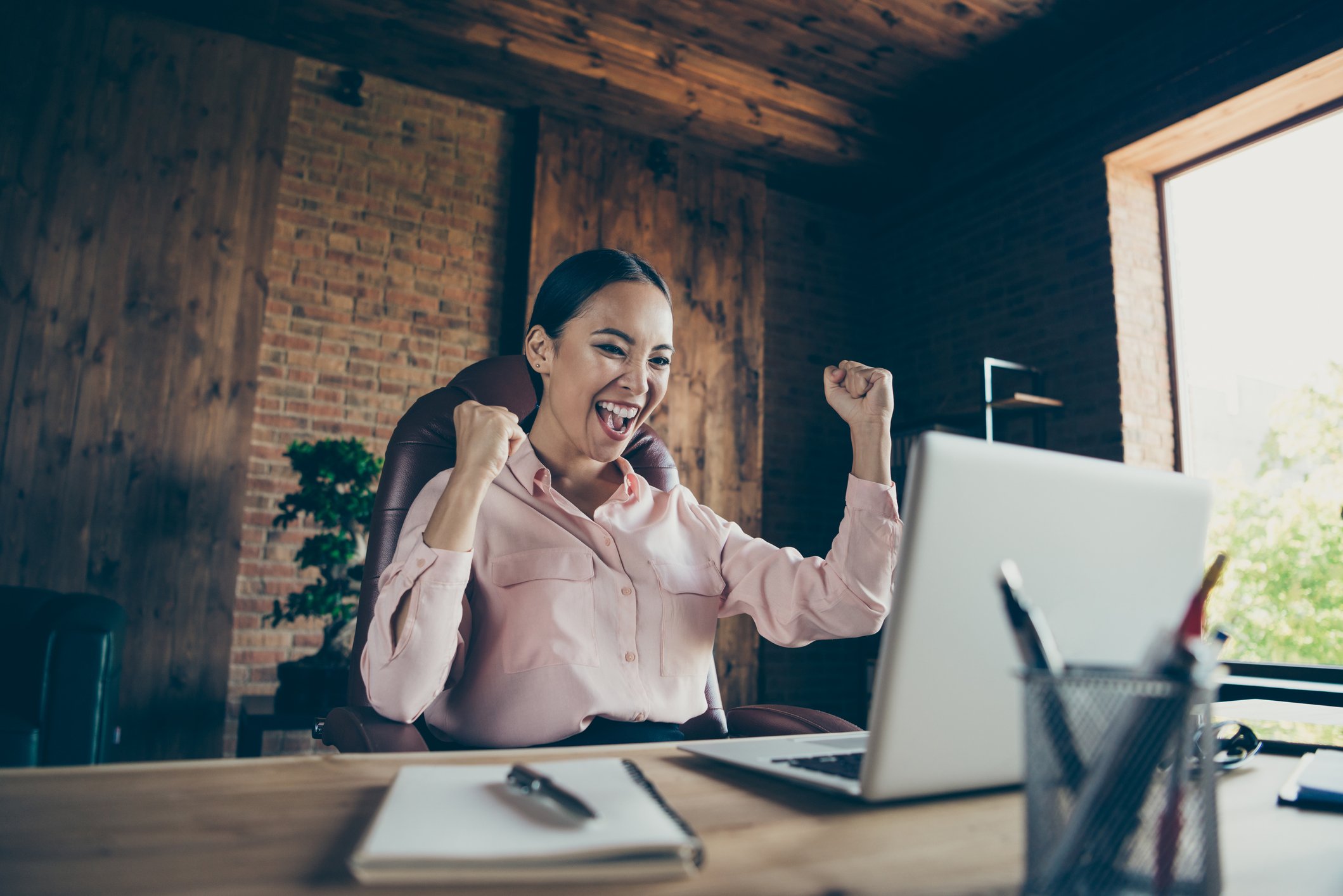 Happy investor cheering at a desk looking at a computer screen.
