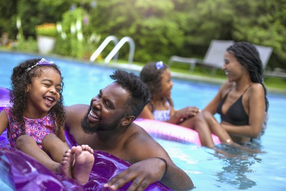 A family in a pool with the two children using floats.