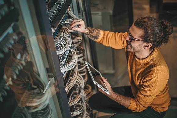 Person working at server rack in data center.