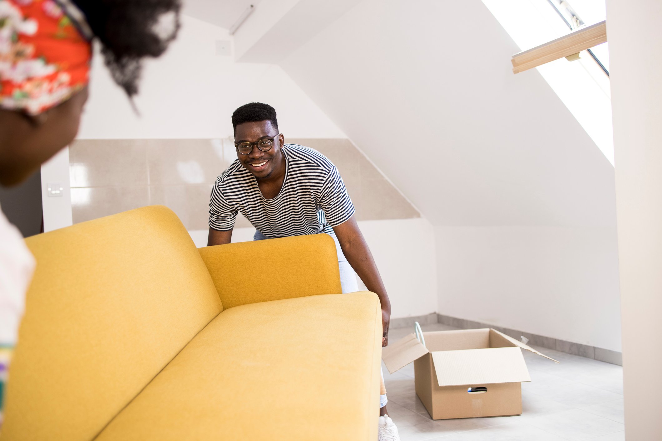 Two people moving a sofa into a room.