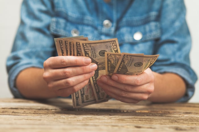 A person holding $50 bills and counting them.