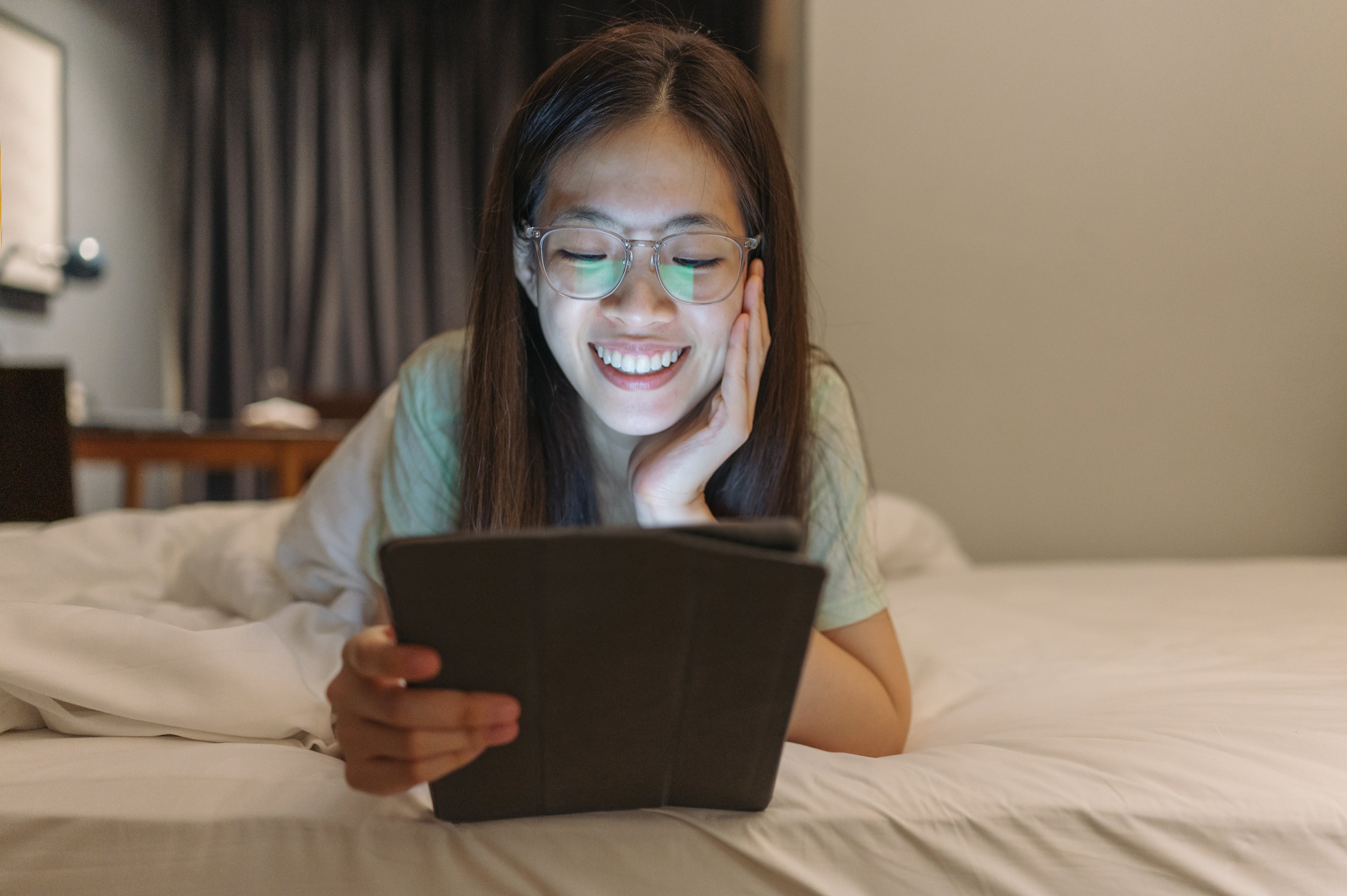 Someone laying on a bed looking at a tablet