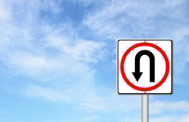 U-turn traffic sign under a blue sky.