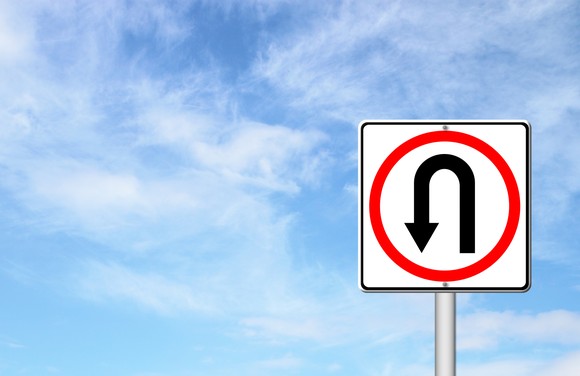 U-turn traffic sign under a blue sky.