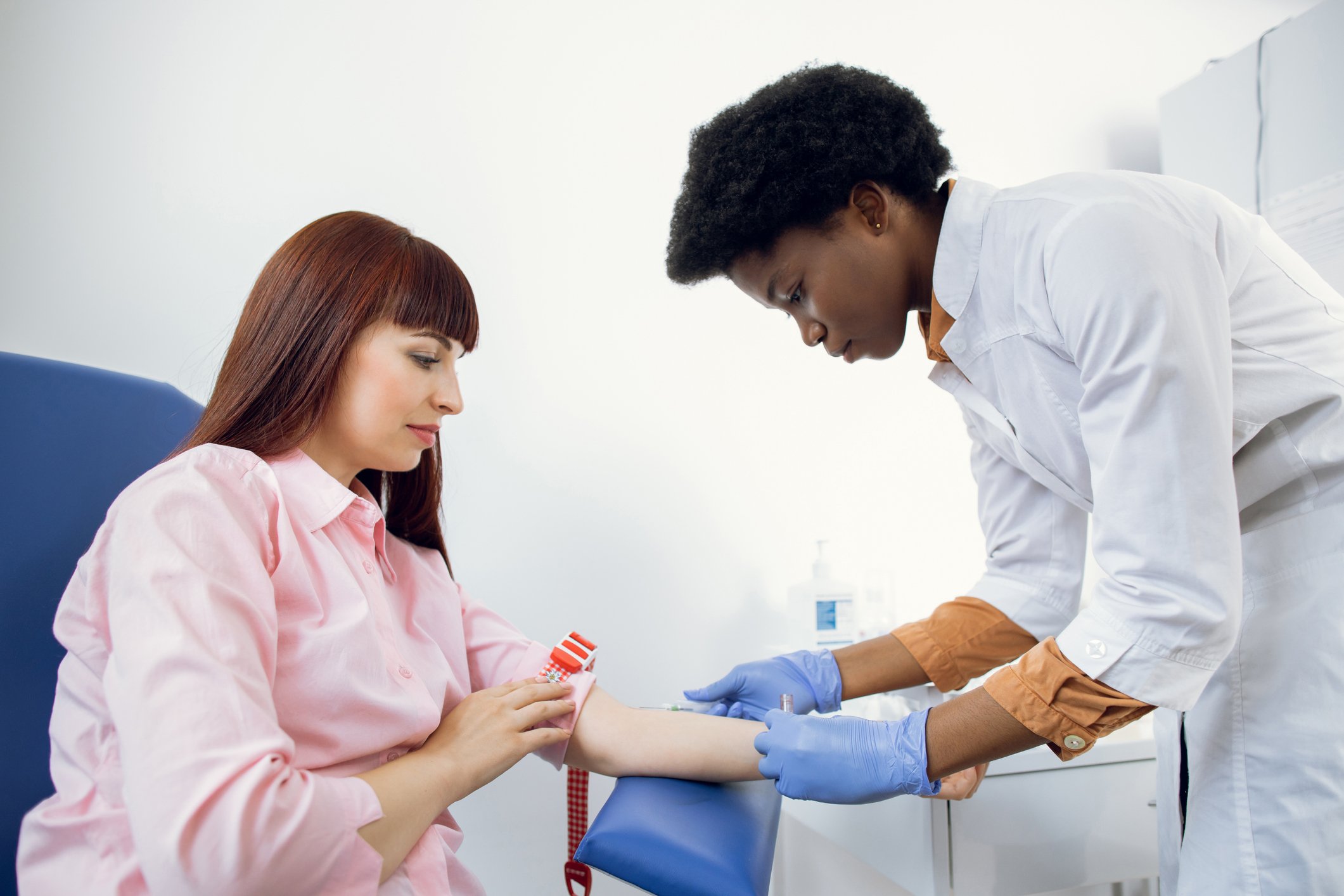 A medical professional draws blood from a patient for a medical screening.
