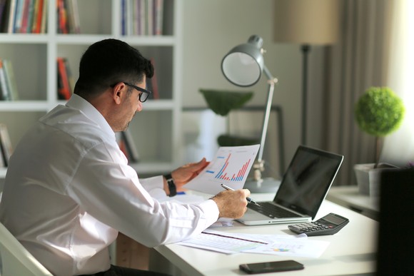 An investor reviews financial charts at desk.