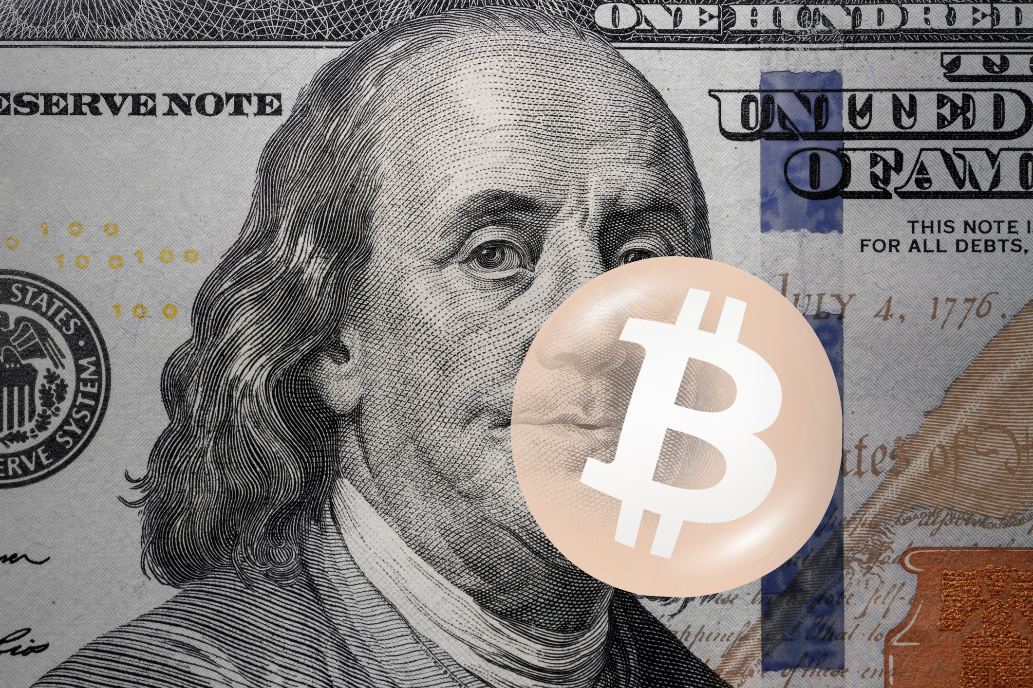 Bitcoin logo on top of a $100 bill.