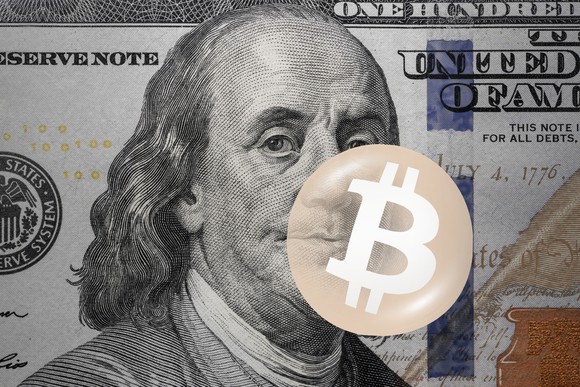 Bitcoin logo on top of a $100 bill.