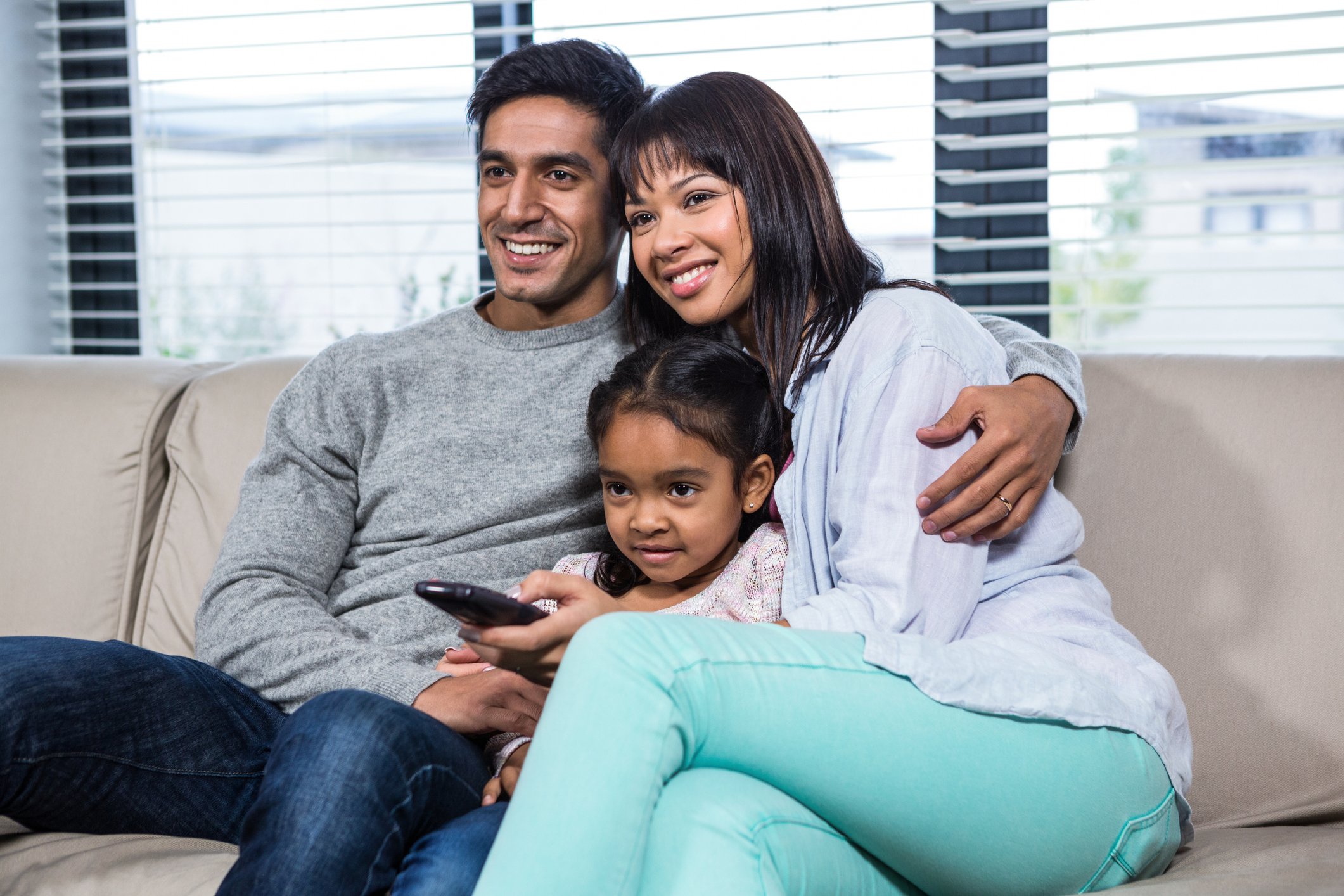 A family on a couch watches television.