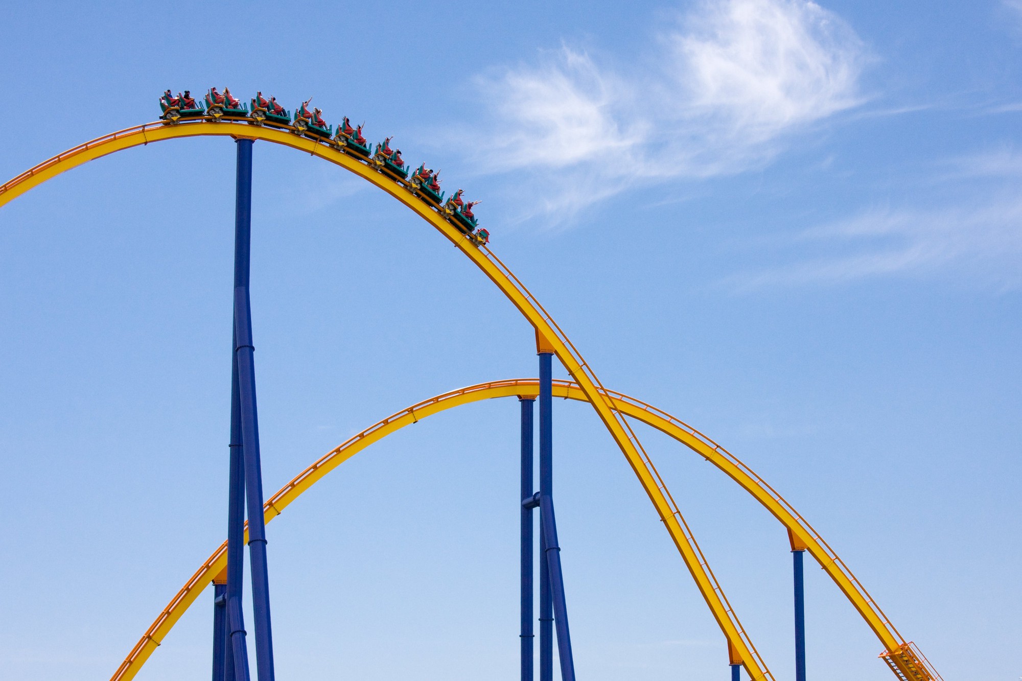 A yellow and blue roller coaster with a bright blue sky in the background. 