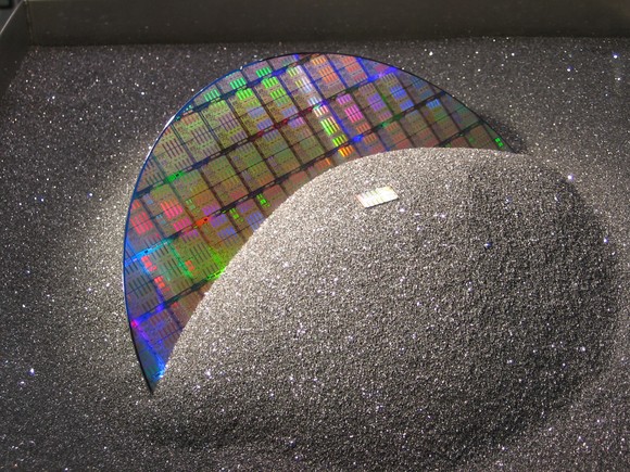 A semiconductor wafer emerges from a pile of ground silicon. 