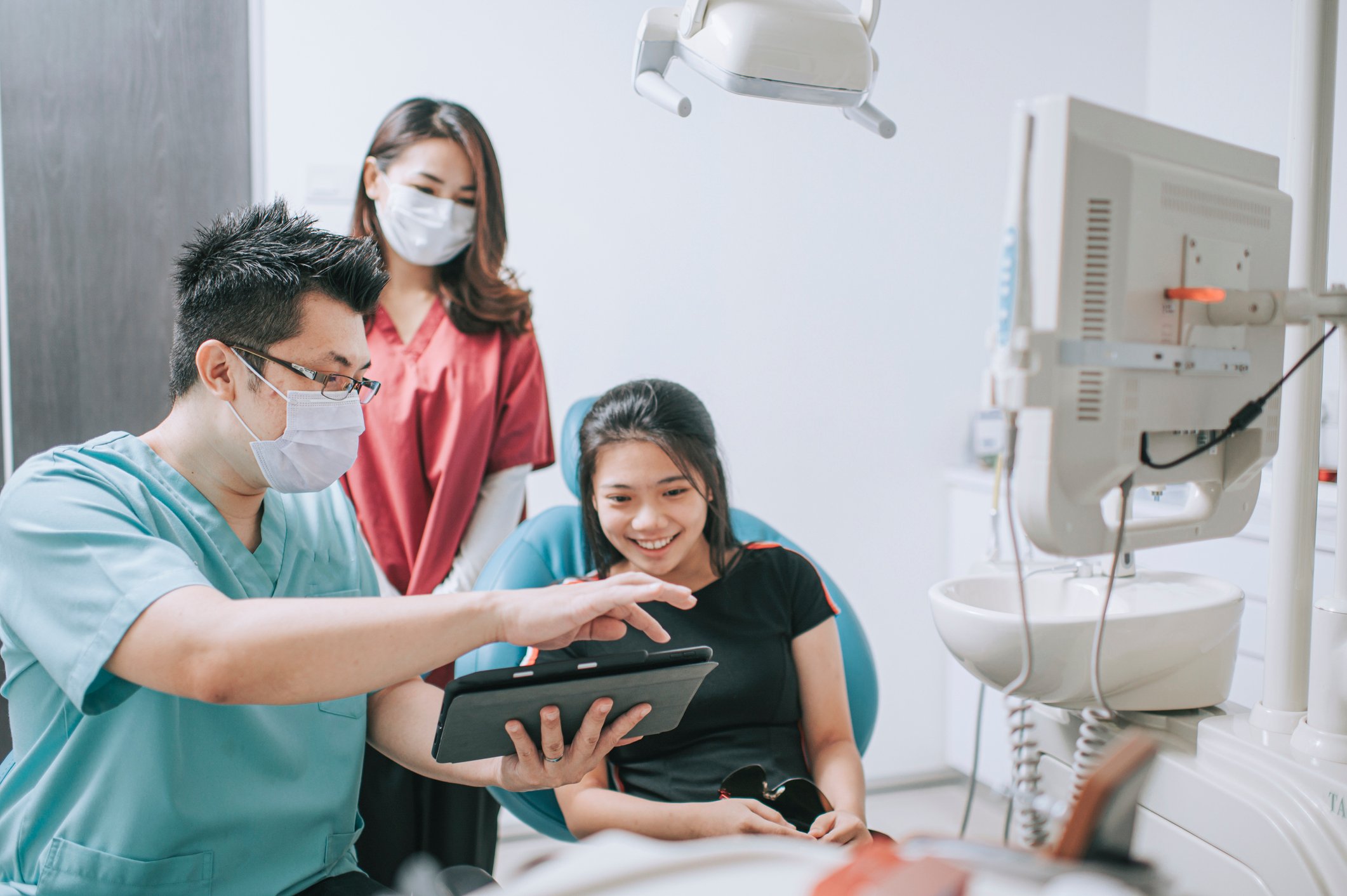 Dentist showing something to a patient on a tablet.