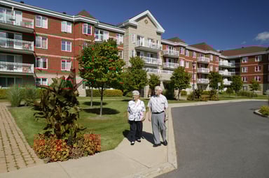 People walking in front of a housing complex.