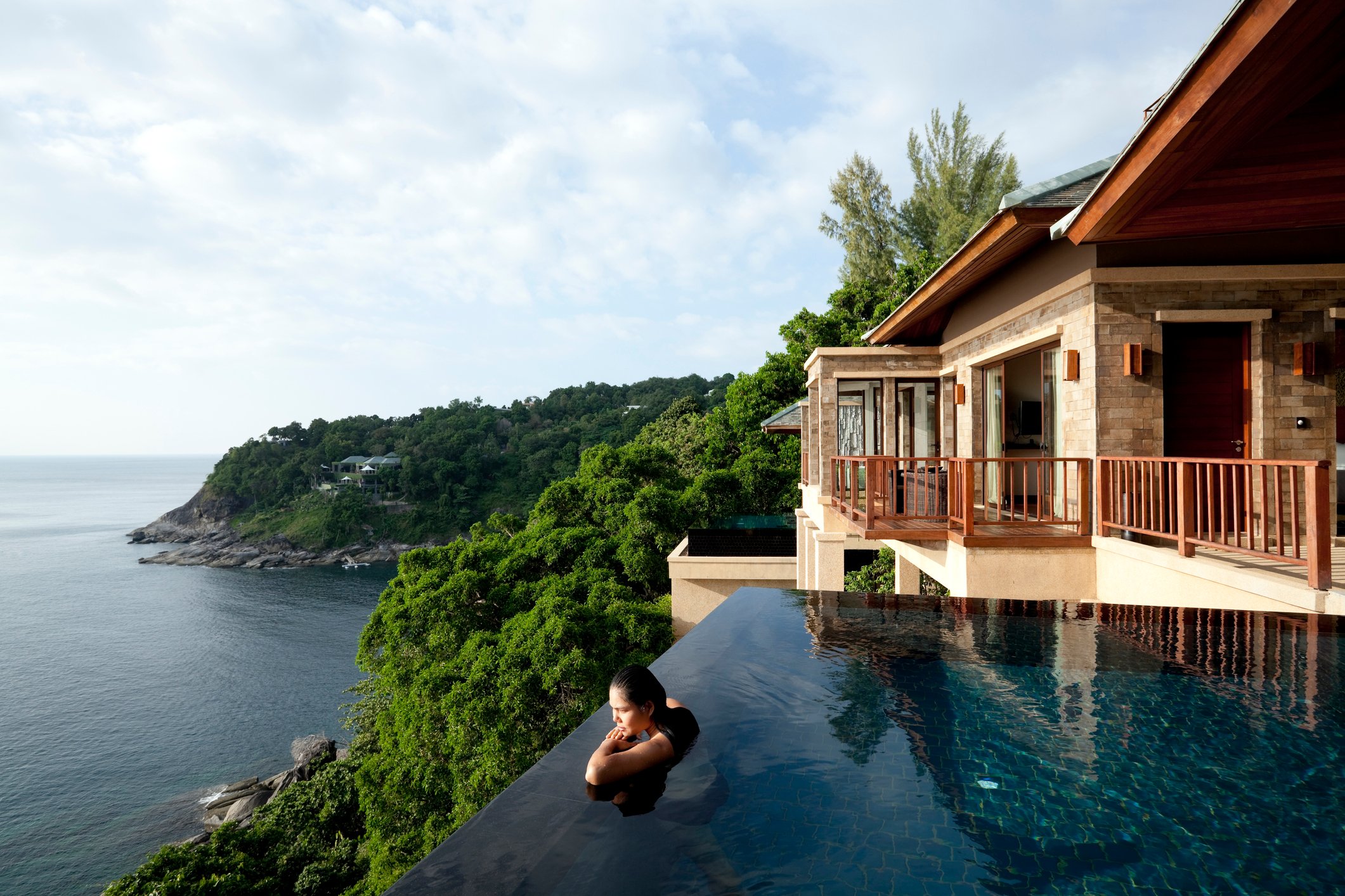 A person in an infinity pool overlooking the ocean.