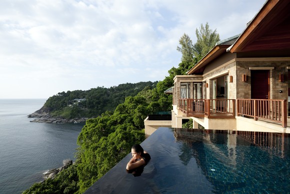 A person in an infinity pool overlooking the ocean.