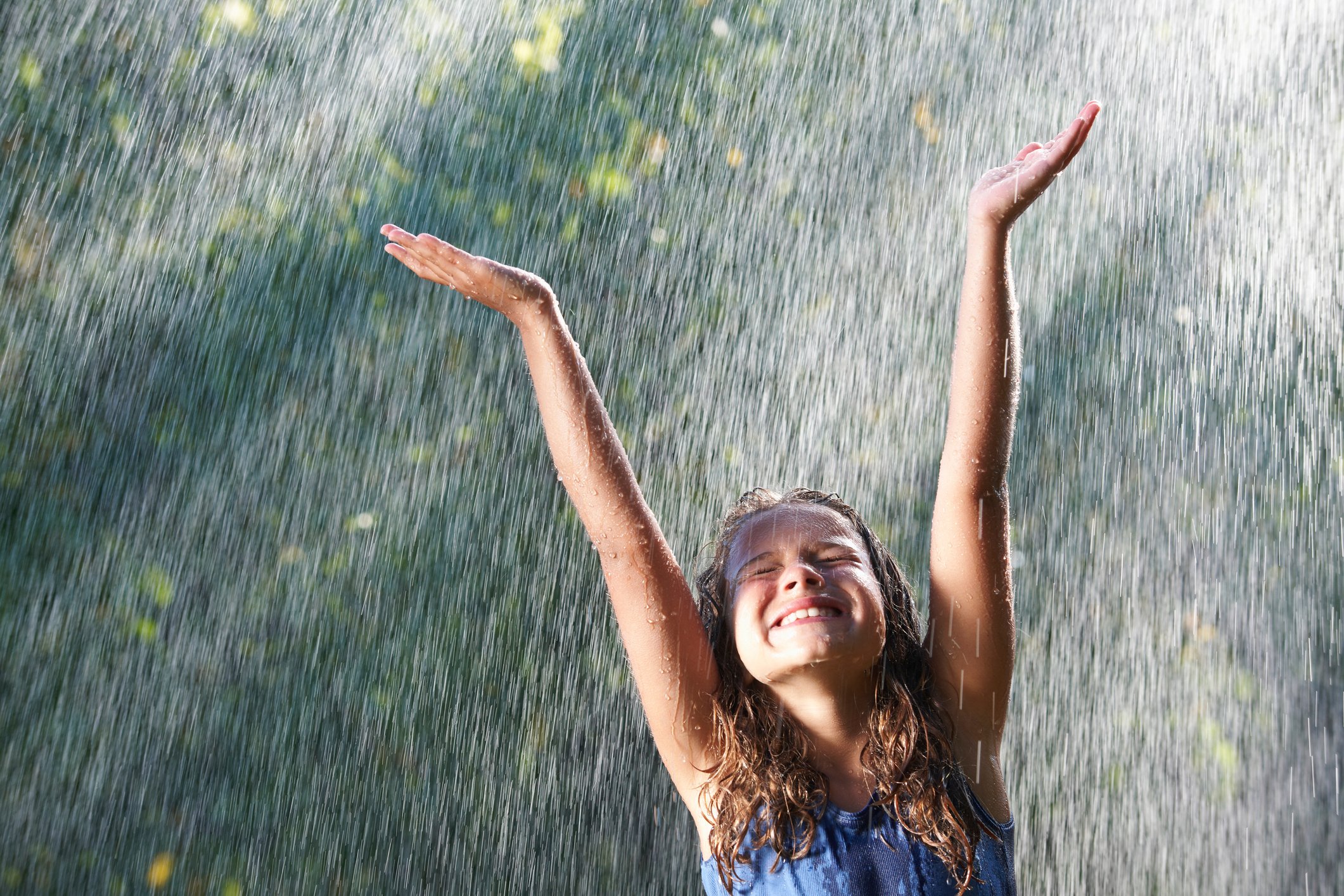 A smiling person playing in the rain.