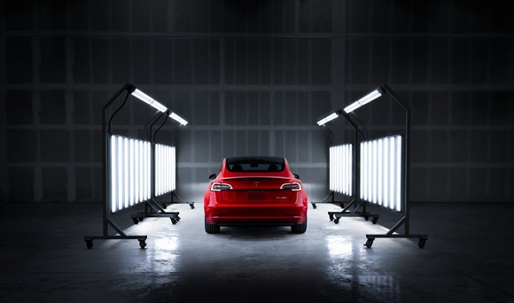 Rear view of red Tesla under body shop service lights.  