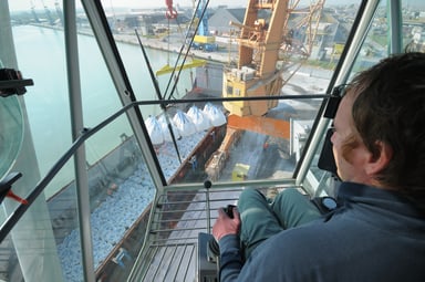 Crane operator loading a dry bulk cargo ship.