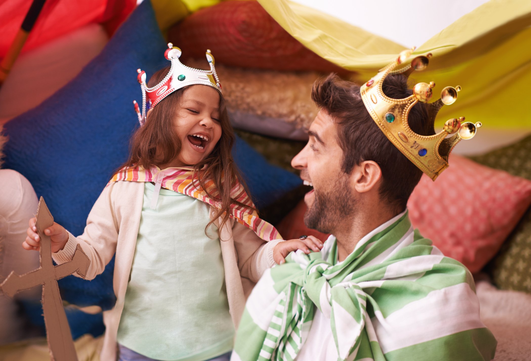 An adult and child smile while playing dress-up.
