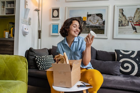 Person unboxing a cup from a package on the couch. 