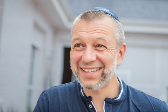 Person smiling in front of house.