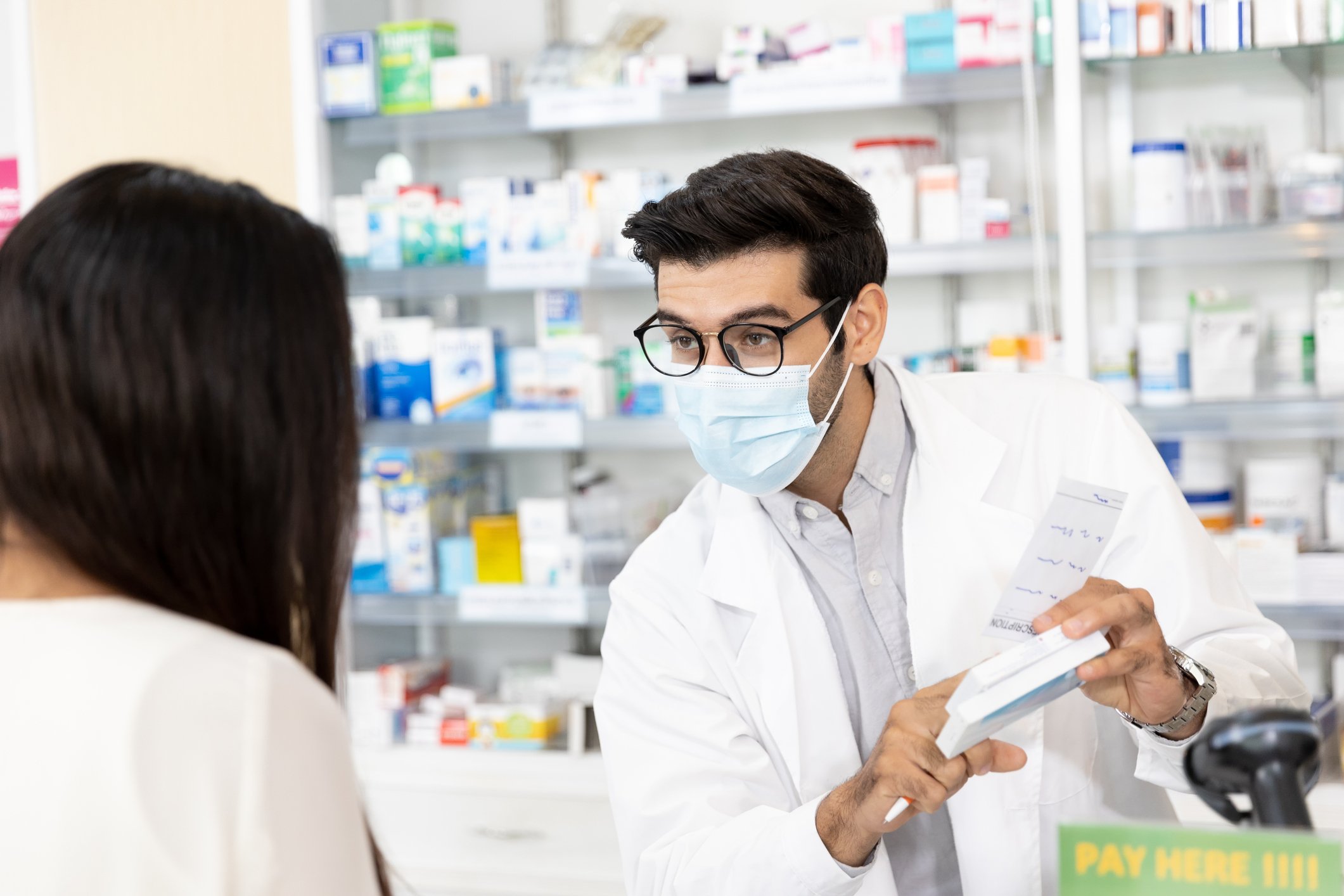 A person picks up a prescription at a pharmacy.