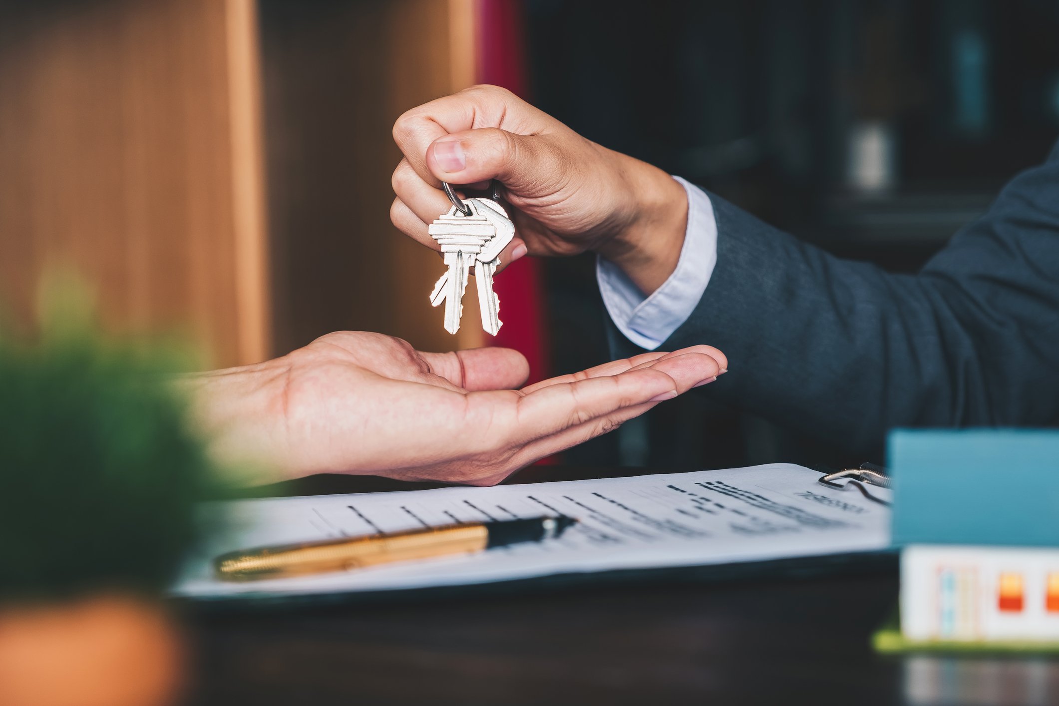 A seller handing keys to a buyer after a real estate sale.