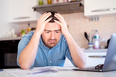 frustrated investor computer paper hands on head