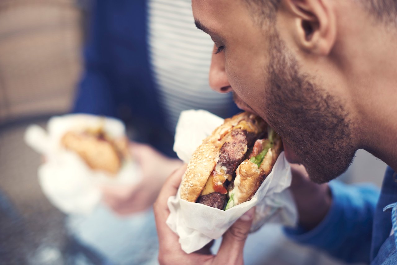 man eating hamburger fast food getty