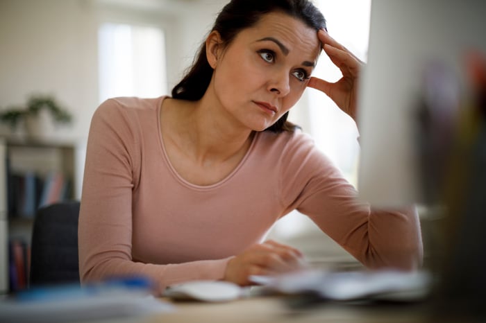 A person with a concerned expression looking at a PC monitor.