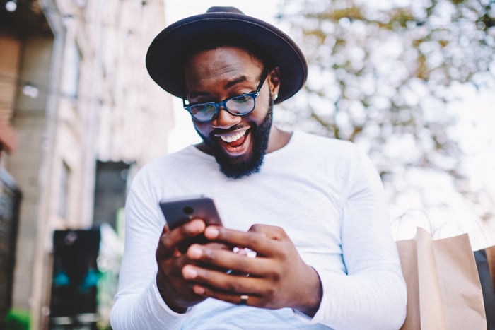 A person reacts happily while looking at a phone.