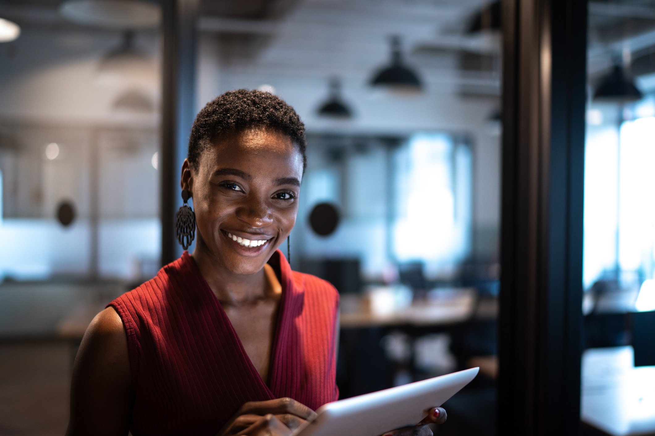 Smiling person holding tablet in café. 
