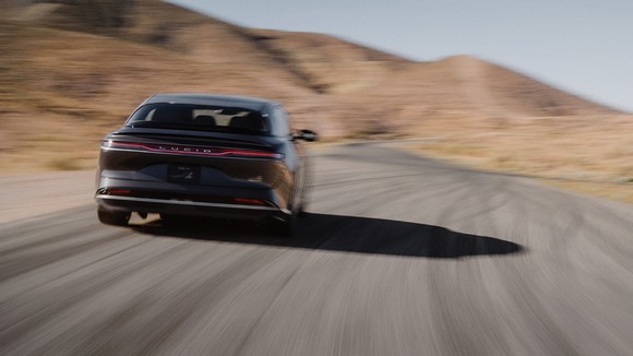 Rear view of Lucid Grand Touring sedan on scenic highway.