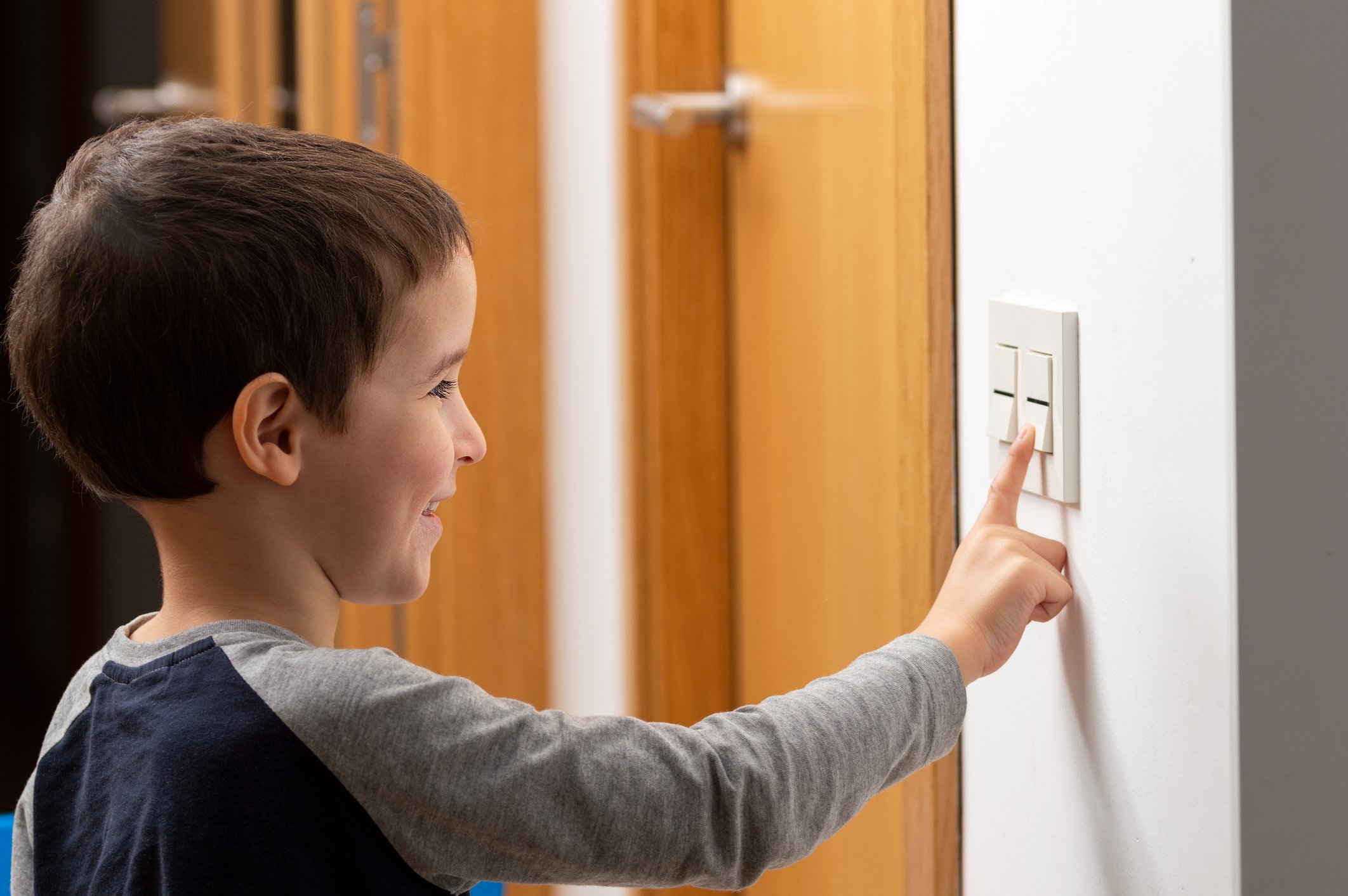 a little child switching a light off in home.