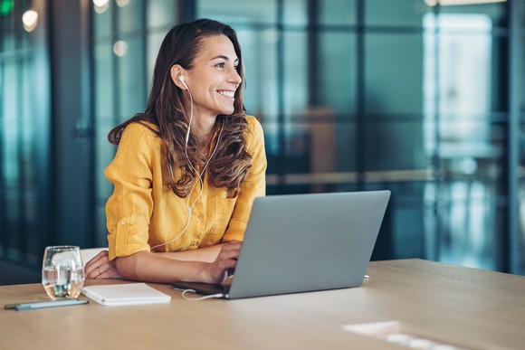 A smiling person uses a laptop computer.