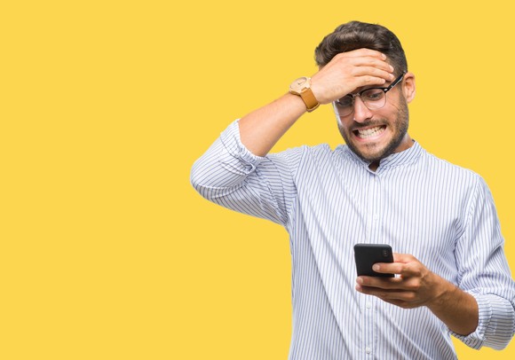 A person looking at a phone and holding their head.