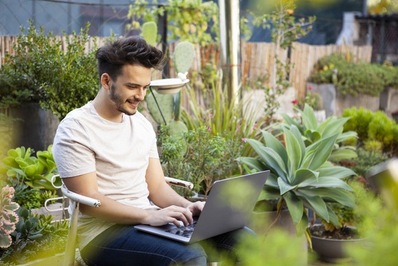 An investor browses his crypto portfolio outside in a rooftop garden.