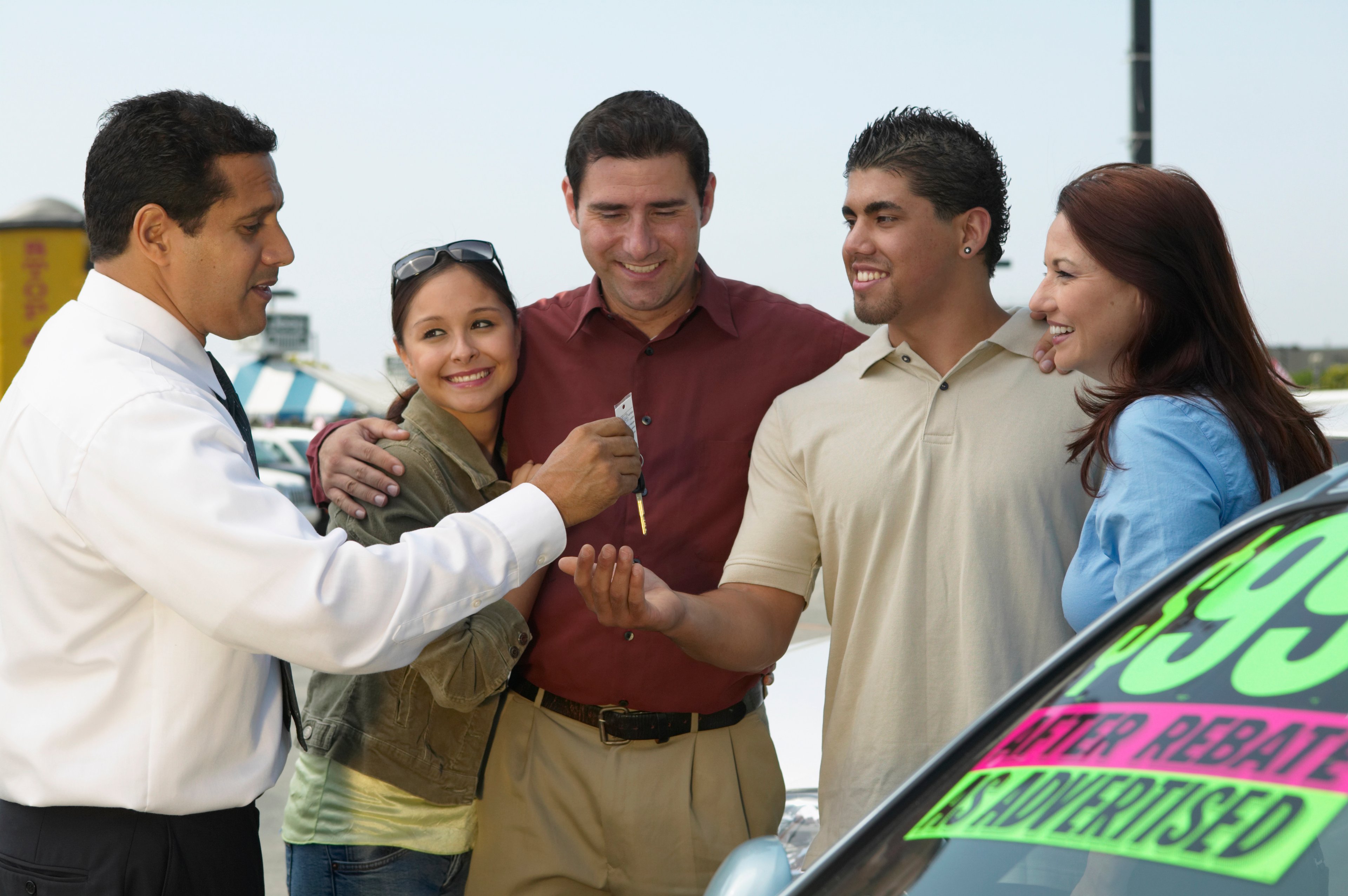 A group of people shopping for a used car.