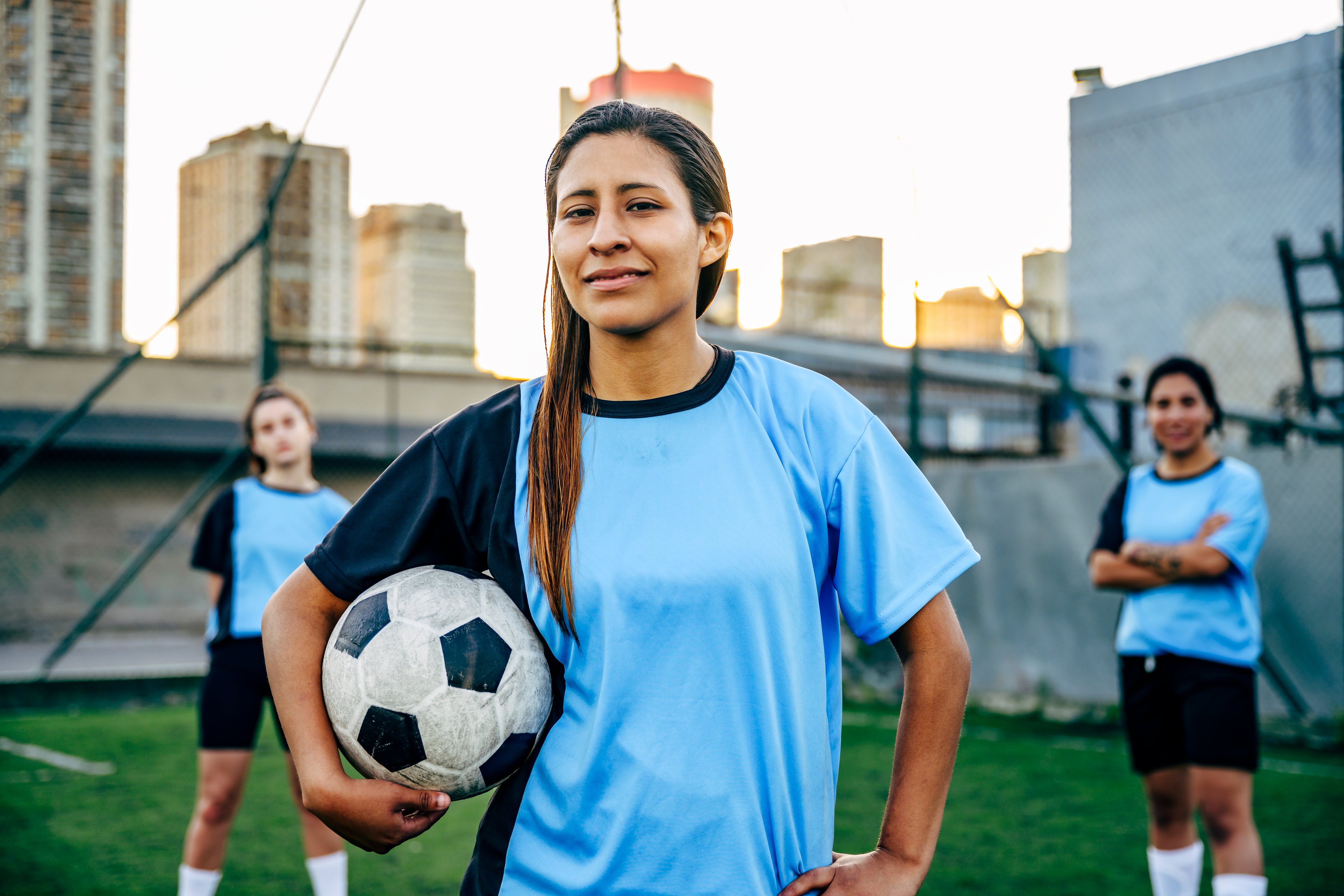 Young soccer player with ball standing with teammates on an urban soccer pitch.