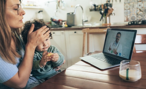 Person and sick baby talking to doctor via laptop.