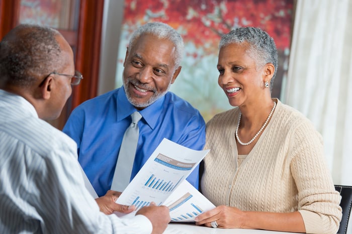 Three people discussing financial paperwork.