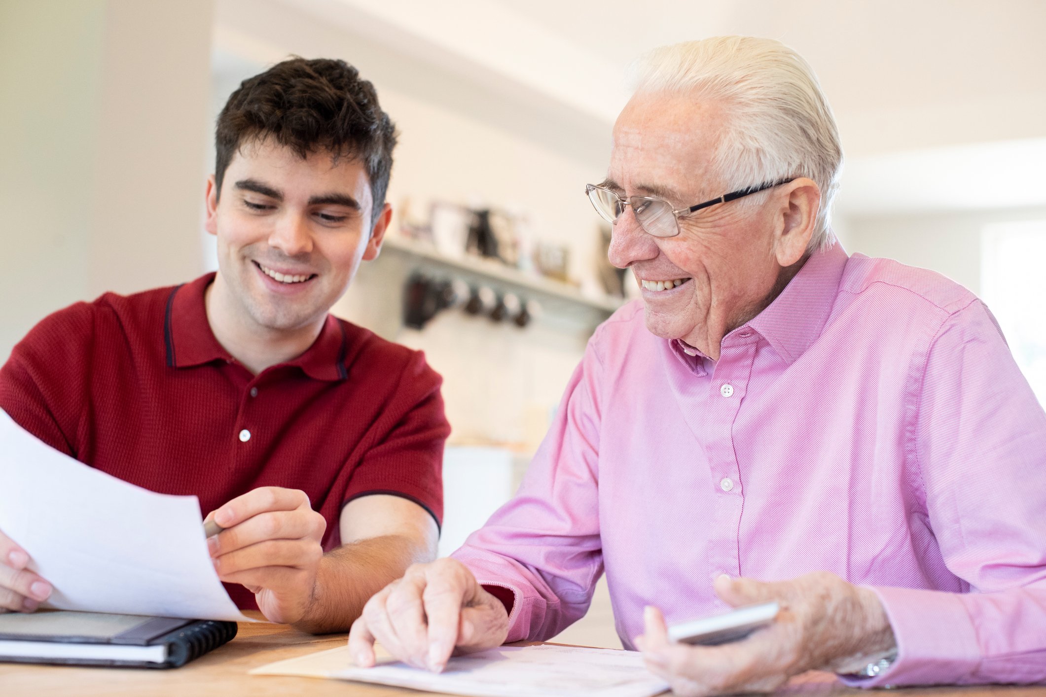 Younger investor reviewing financial information with an older investor at a desk.