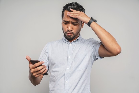 A person with an upset expression while looking at a phone.