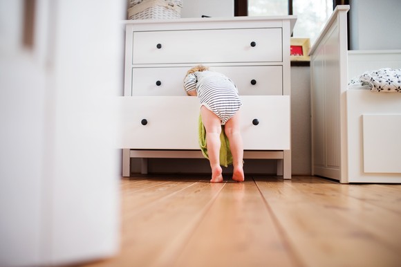 Child looking in the bottom drawer of a dresser