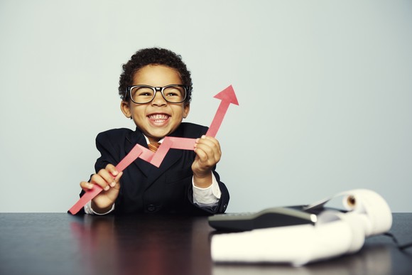 A child holds a cutout of a rising chart.