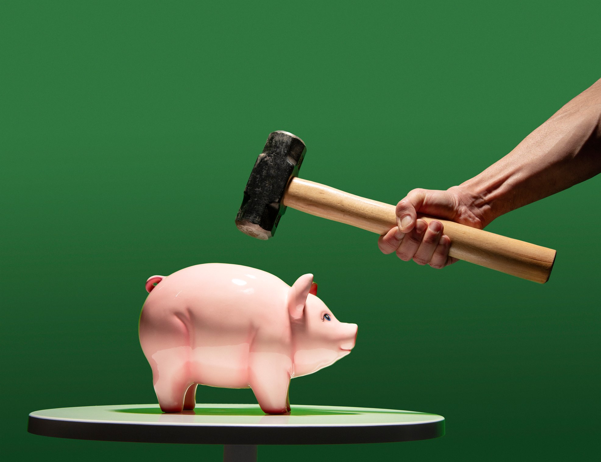Person with hammer threatening piggy bank.