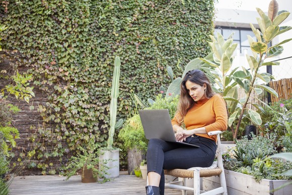 A young person sitting outside using a laptop.
