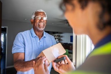 Woman delivering package to elderly man